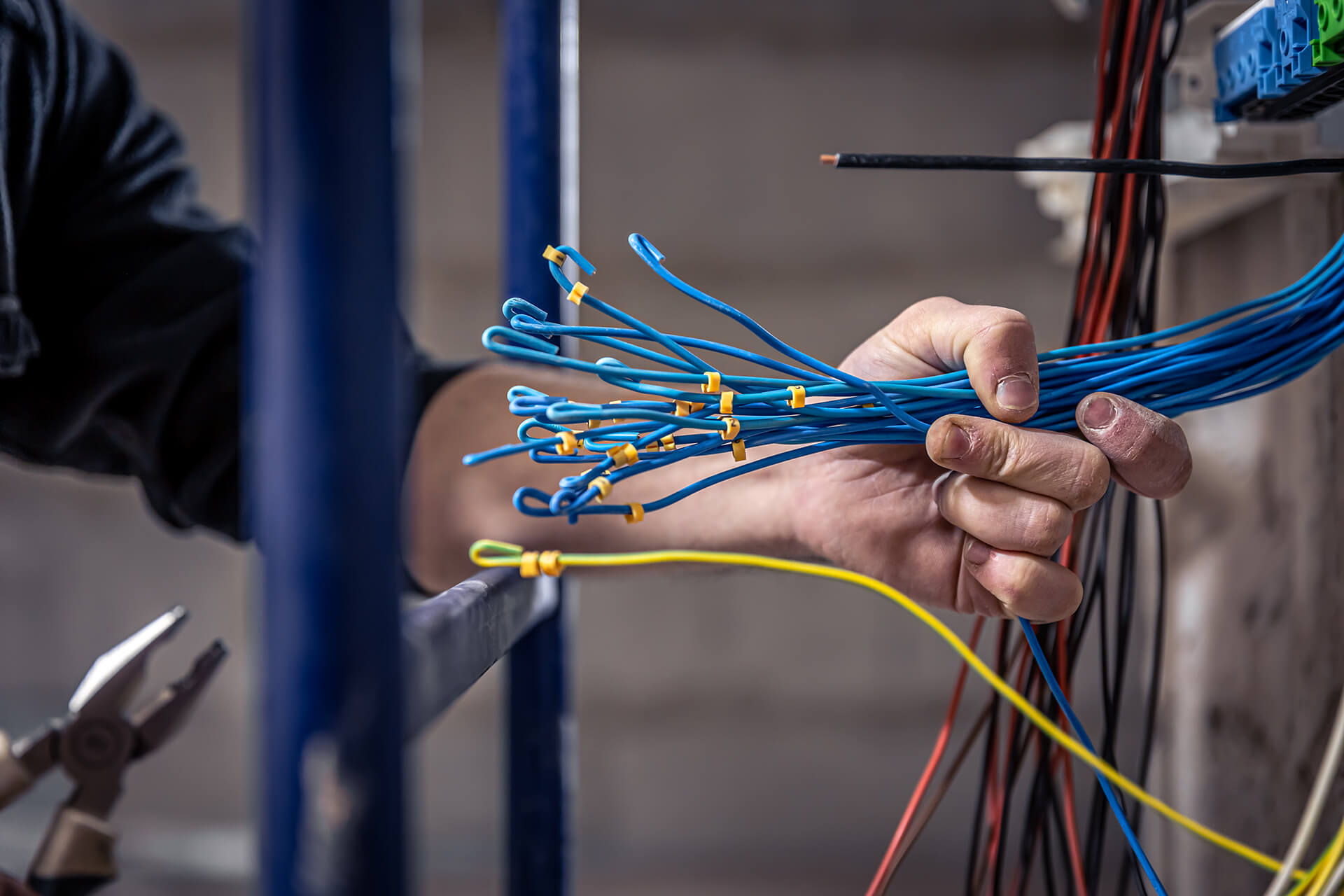 Electrician works switchboard with electrical connecting cable